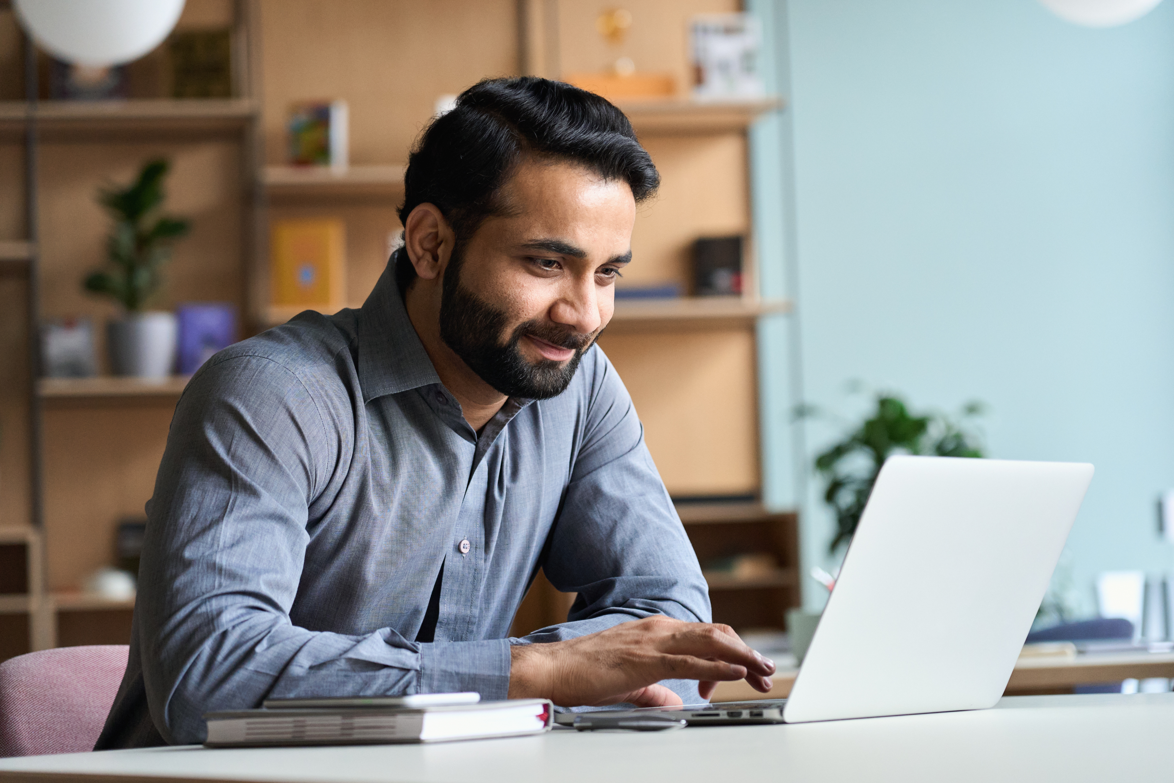 Hombre sonriendo mientras trabaja en una laptop en un escritorio