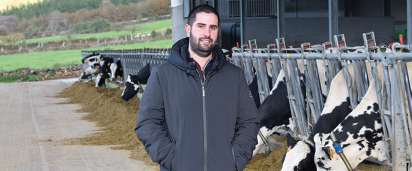 Ganadero de pie junto a vacas lecheras en una explotación ganadera