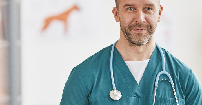 Retrato de veterinario. Veterinario con bata y estetoscopio, sonriendo en una clínica