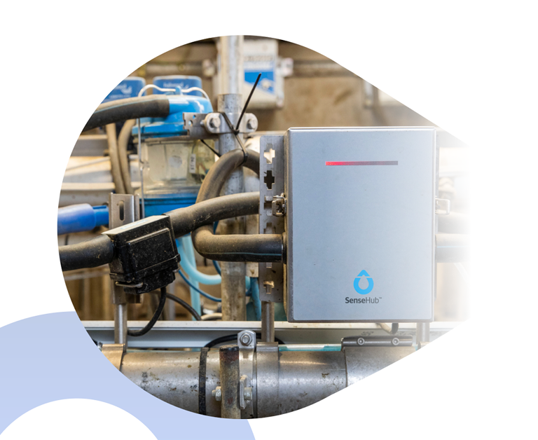 Dispositivo de control SenseHub instalado en una tubería industrial dentro de una planta de procesamiento lácteo.